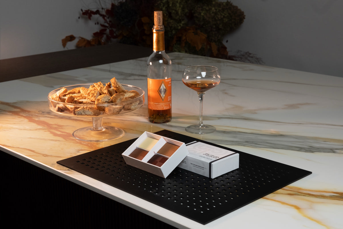 A Taste of Tuscany box of 4 filled bars on a marble table with cantucci and a glass of Vin Santo
