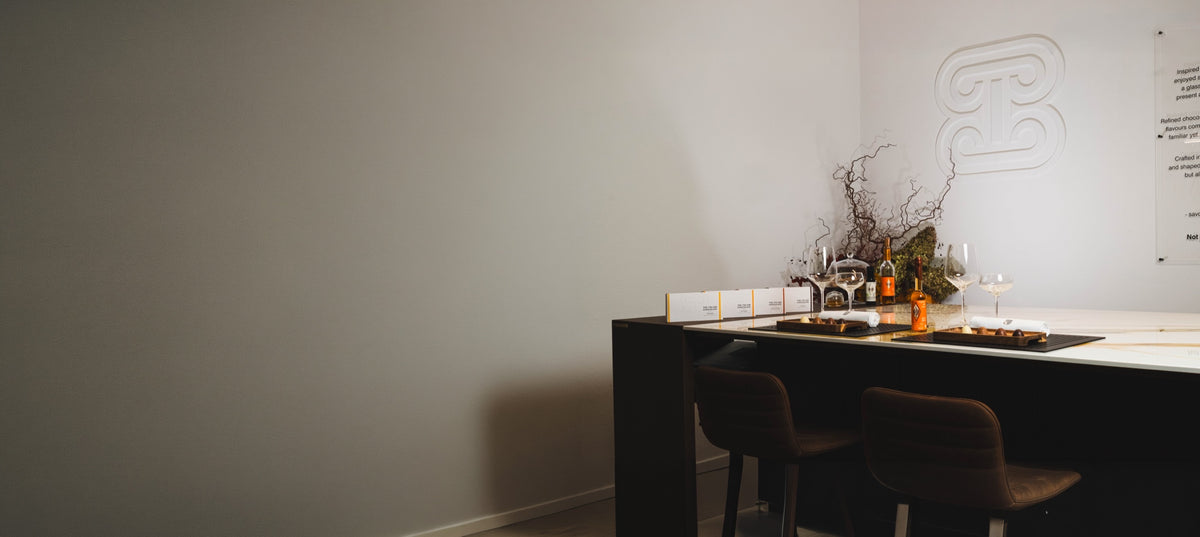 Tasting table set for the Open Day at The Atelier 1971 in Florence: chocolate boxes, Vin Santo, glasses and the brandmark on the wall