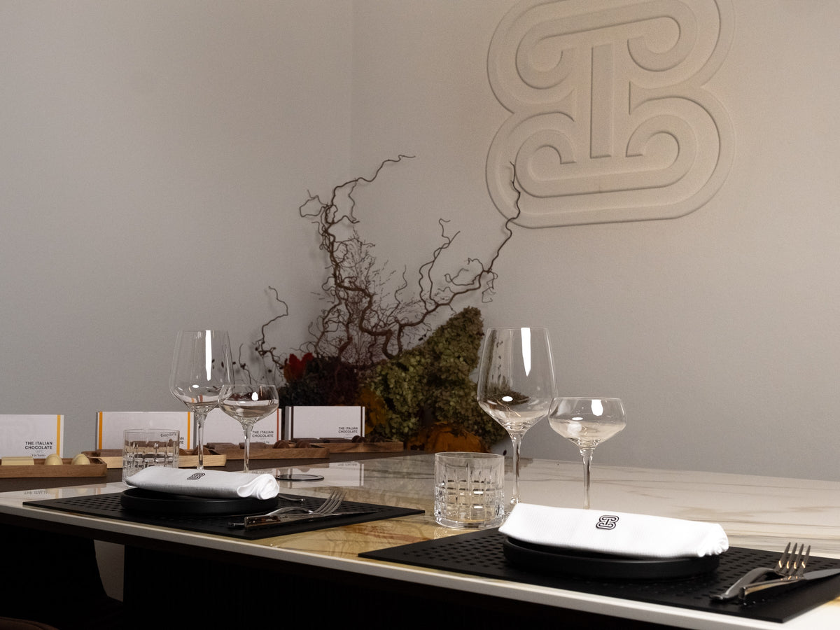 The table laid for a private group at The Atelier 1971, with place cards, wine glasses and the brand monogram on the wall