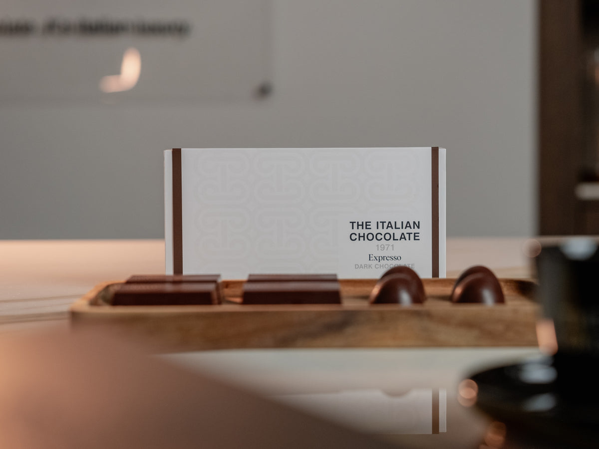 Chocolate bars and pralines on a walnut tray in front of their box, on the marble counter of The Atelier 1971 in Florence